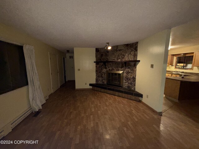 9231 Campbell Ter, Anchorage, AK 99515 - unfurnished living room featuring wood finished floors, a textured ceiling, and a stone fireplace
