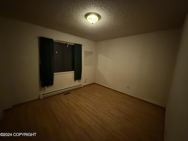 9231 Campbell Ter, Anchorage, AK 99515 - unfurnished room with a baseboard radiator, wood finished floors, and a textured ceiling