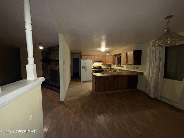 9231 Campbell Ter, Anchorage, AK 99515 - kitchen featuring white fridge with ice dispenser, a peninsula, black range with electric cooktop, a fireplace with raised hearth, and wood finished floors