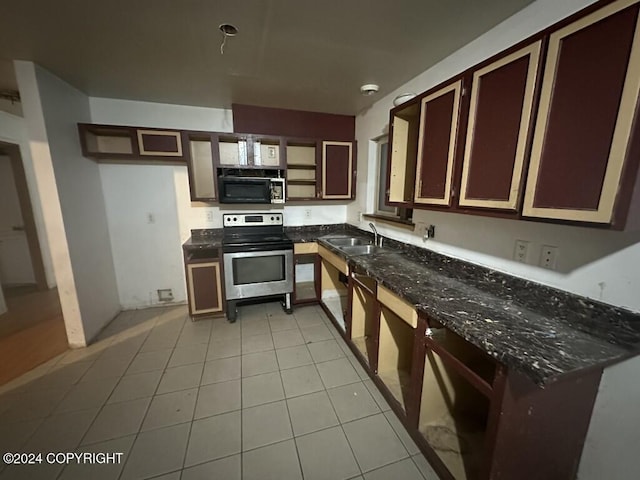 kitchen with stainless steel electric range oven, sink, light tile patterned floors, and dark stone counters