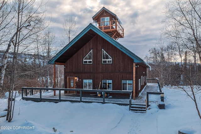 snow covered rear of property featuring a balcony