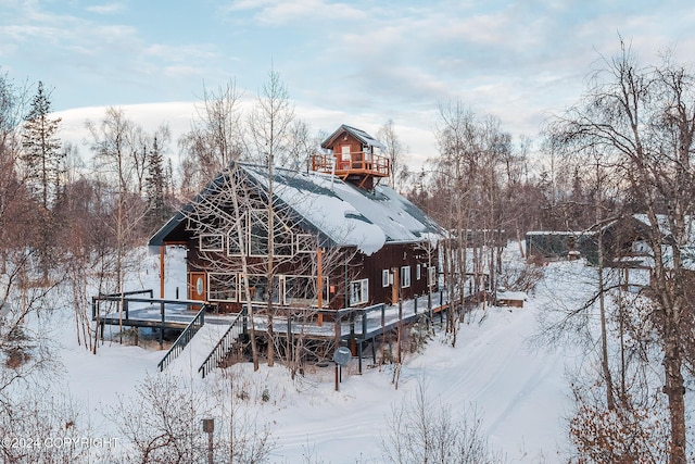 snow covered back of property featuring a deck