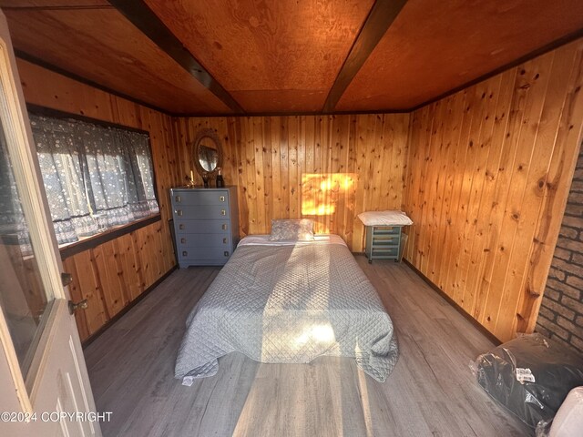 bedroom with hardwood / wood-style floors, wood ceiling, and wooden walls