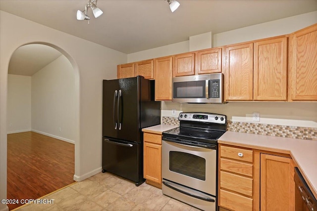 kitchen with appliances with stainless steel finishes, an inviting chandelier, light hardwood / wood-style flooring, and light brown cabinetry