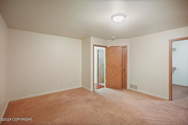 unfurnished bedroom featuring light carpet, a spacious closet, and a closet