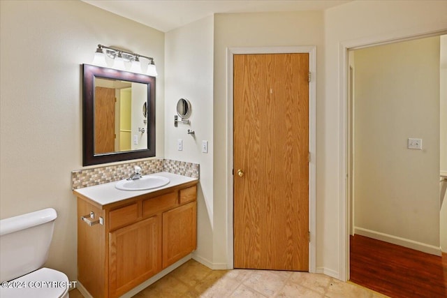 bathroom with tasteful backsplash, toilet, vanity, and hardwood / wood-style flooring