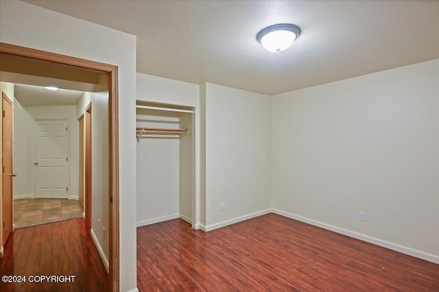 unfurnished bedroom featuring dark hardwood / wood-style floors and a closet