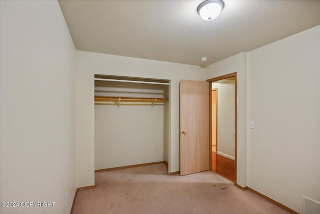 unfurnished bedroom with a closet and light colored carpet