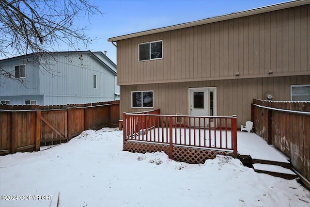 snow covered house with a wooden deck