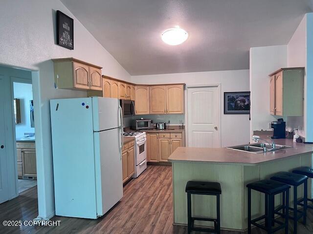 4570 S Navigators Cir, Wasilla, AK 99623 - kitchen featuring white appliances, a peninsula, a sink, vaulted ceiling, and dark wood-style flooring