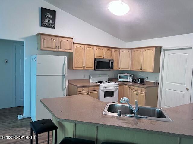 4570 S Navigators Cir, Wasilla, AK 99623 - kitchen featuring white appliances, a sink, lofted ceiling, a breakfast bar area, and dark wood finished floors