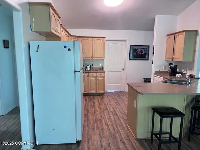 4570 S Navigators Cir, Wasilla, AK 99623 - kitchen with freestanding refrigerator, dark wood-style floors, a kitchen breakfast bar, a peninsula, and a sink
