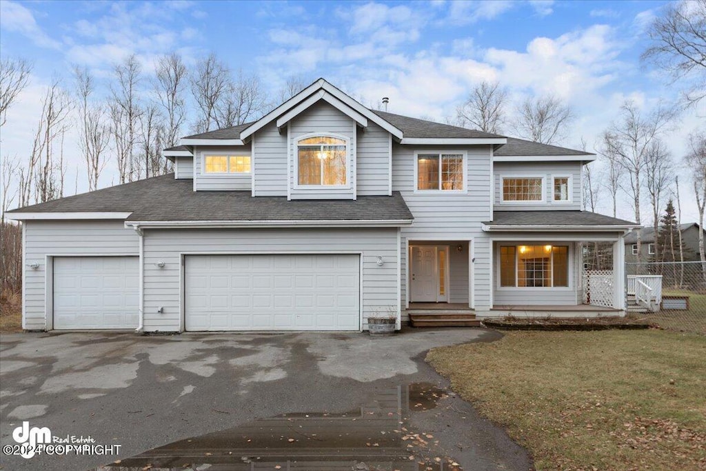 view of front of property featuring a garage, a front lawn, and covered porch