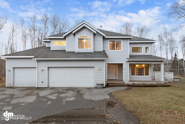 view of front of property featuring a garage, a front lawn, and covered porch