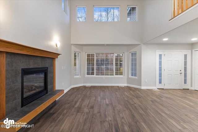 unfurnished living room featuring a healthy amount of sunlight, dark hardwood / wood-style floors, and a fireplace