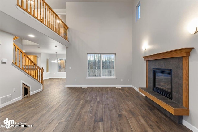 unfurnished living room featuring dark hardwood / wood-style flooring, a fireplace, a high ceiling, and plenty of natural light