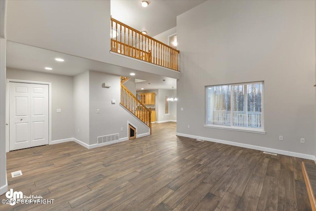 unfurnished living room with dark hardwood / wood-style flooring and a towering ceiling