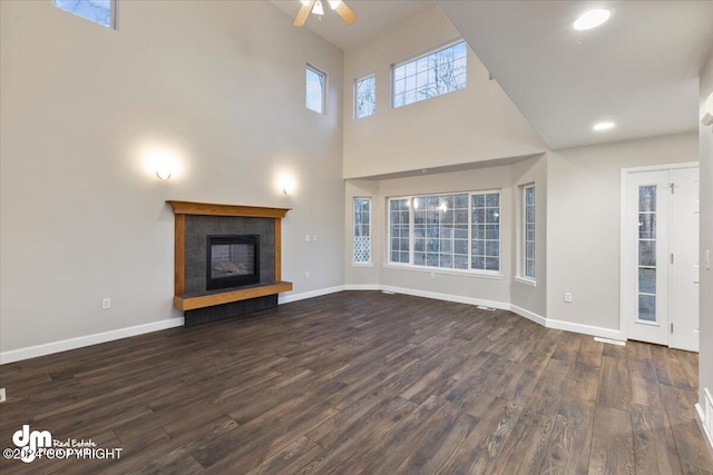 unfurnished living room featuring dark hardwood / wood-style floors, ceiling fan, and a high ceiling