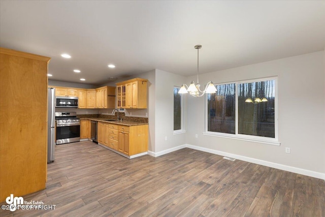 kitchen with decorative light fixtures, sink, stainless steel appliances, dark wood-type flooring, and an inviting chandelier