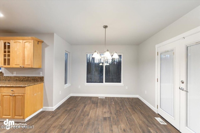 unfurnished dining area featuring dark wood-type flooring and a notable chandelier