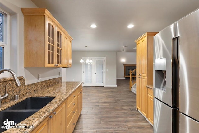 kitchen with dark hardwood / wood-style floors, decorative light fixtures, sink, stainless steel fridge with ice dispenser, and light stone countertops