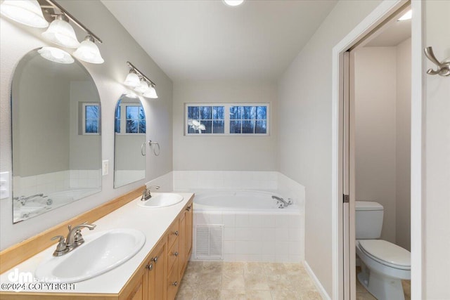 bathroom featuring vanity, a relaxing tiled tub, and toilet