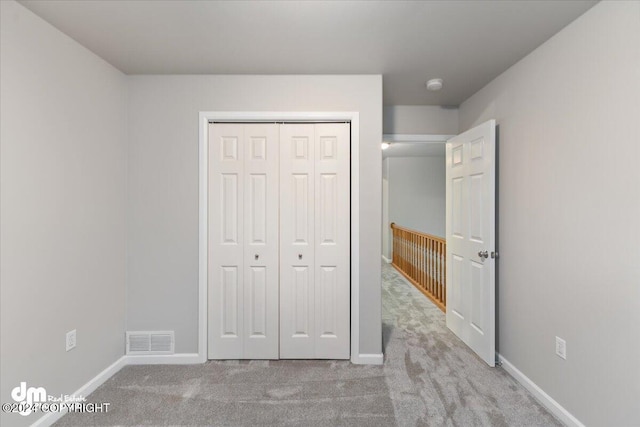 unfurnished bedroom featuring light colored carpet and a closet