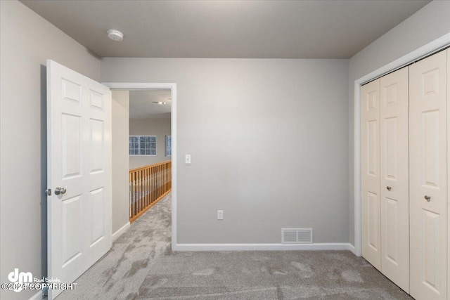 unfurnished bedroom featuring light colored carpet and a closet