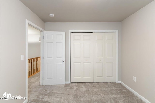 unfurnished bedroom with light carpet and a closet