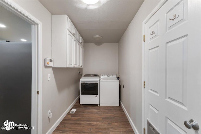 washroom with dark wood-type flooring, cabinets, and washing machine and clothes dryer