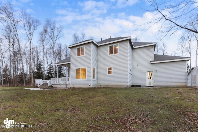 back of property with a wooden deck and a lawn