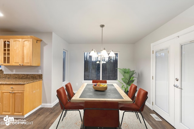 dining area with dark hardwood / wood-style flooring and a notable chandelier