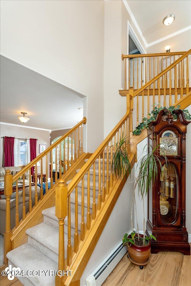 stairway with a baseboard radiator and hardwood / wood-style floors