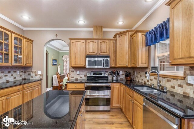 kitchen with ornamental molding, appliances with stainless steel finishes, sink, and dark stone countertops