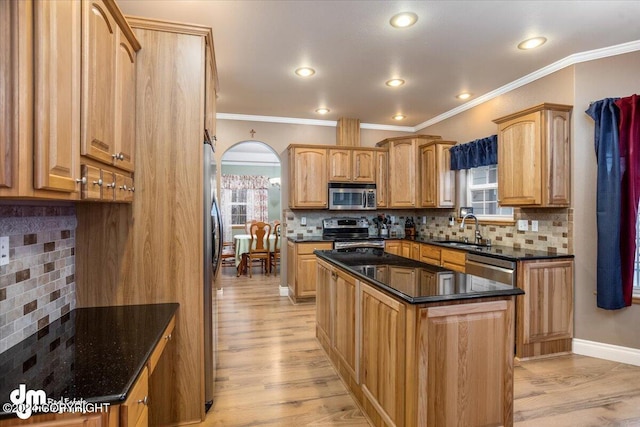 kitchen featuring sink, light hardwood / wood-style flooring, appliances with stainless steel finishes, a kitchen island, and decorative backsplash