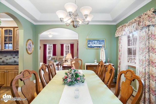 dining space with a notable chandelier, ornamental molding, a raised ceiling, and baseboard heating