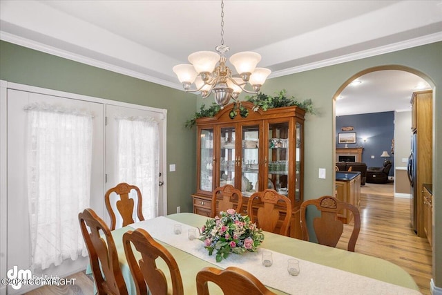 dining room with ornamental molding, a notable chandelier, and light hardwood / wood-style flooring