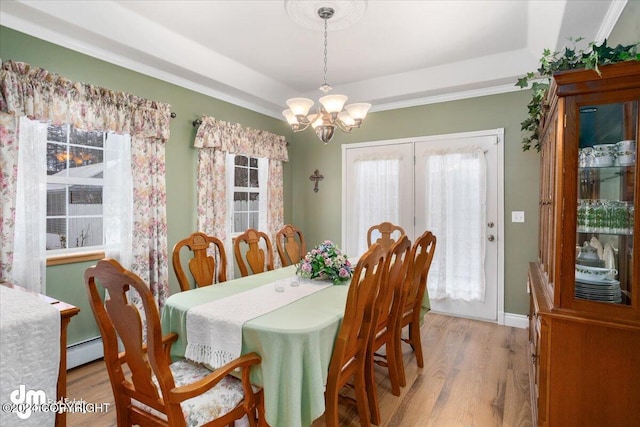 dining space featuring plenty of natural light, a raised ceiling, light hardwood / wood-style floors, and a notable chandelier