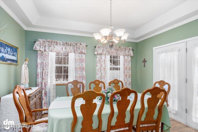 dining area with light hardwood / wood-style flooring, an inviting chandelier, and a tray ceiling