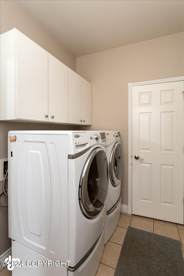 laundry room featuring cabinets, light tile patterned flooring, and separate washer and dryer