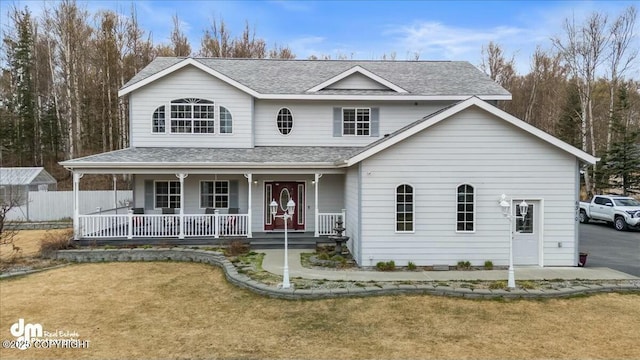 view of front of property featuring covered porch, a shingled roof, and a front yard