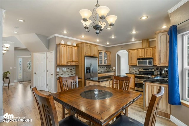dining room featuring an inviting chandelier, light wood-type flooring, baseboards, and arched walkways
