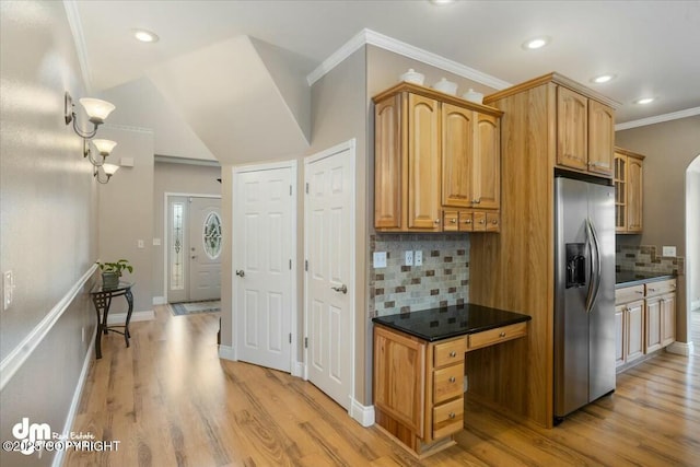 kitchen with light wood-style flooring, ornamental molding, dark countertops, backsplash, and stainless steel refrigerator with ice dispenser