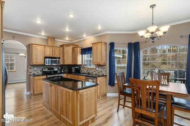kitchen with dark countertops, a sink, appliances with stainless steel finishes, and a chandelier