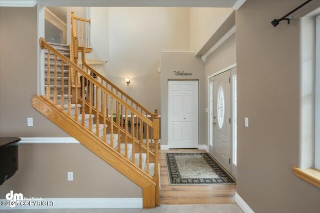 entrance foyer featuring a towering ceiling, stairs, wood finished floors, and baseboards