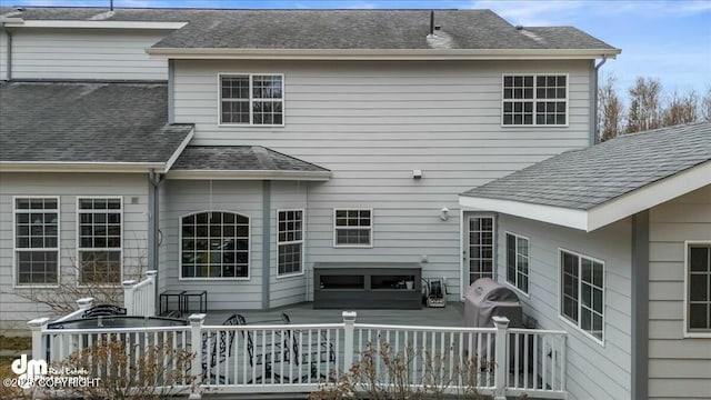 back of property featuring a wooden deck and a hot tub
