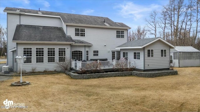 rear view of property with a greenhouse, an outdoor structure, a lawn, central AC, and a deck