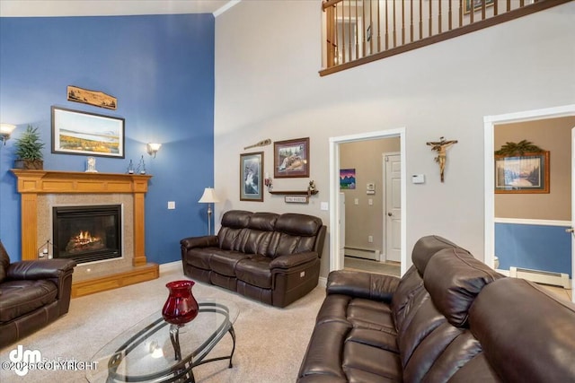 carpeted living area featuring a baseboard radiator, a towering ceiling, a glass covered fireplace, and baseboards