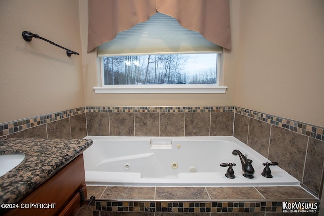 bathroom with vanity, a relaxing tiled tub, and plenty of natural light