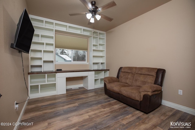 living area featuring built in desk, dark wood-type flooring, and ceiling fan